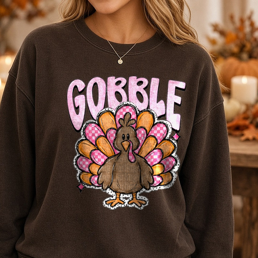 Gobble Cute Turkey Pink Checkered Feathers Thanksgiving DTF transfer shown on a Comfort Colors sweatshirt