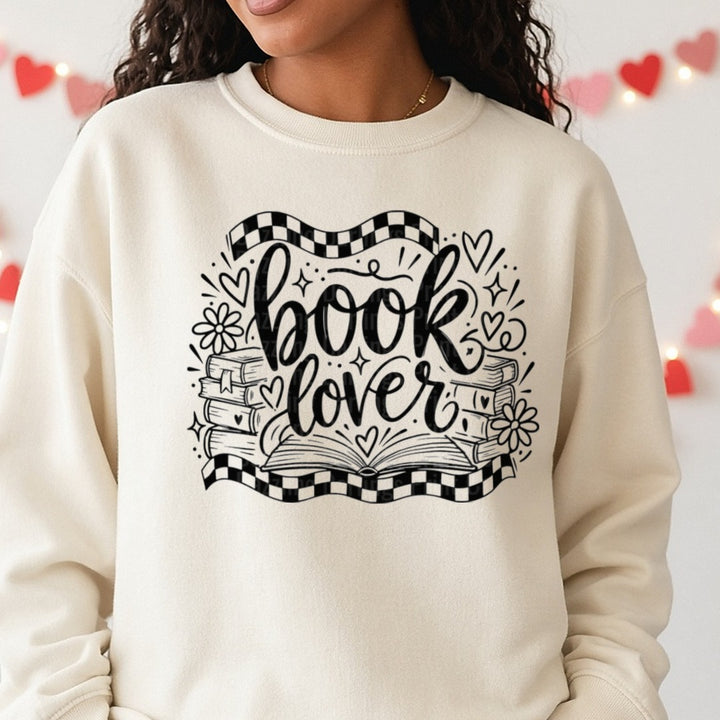Book Lover Script with Stacked Books and Checkered Banner DTF transfer shown on a Comfort Colors sweatshirt