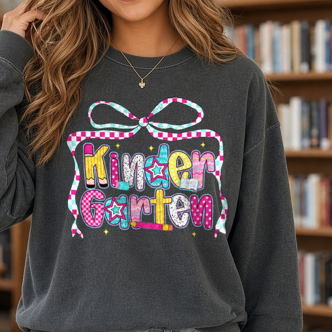 Back To School Kindergarten Checkered Ribbon Bow Patterned Letters DTF transfer shown on a Comfort Colors sweatshirt