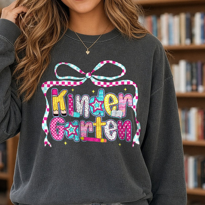 Back To School Kindergarten Checkered Ribbon Bow Patterned Letters DTF transfer shown on a Comfort Colors sweatshirt