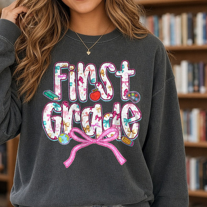 Back To School First Grade Floral Letters Pink Bow Apple DTF transfer shown on a Comfort Colors sweatshirt