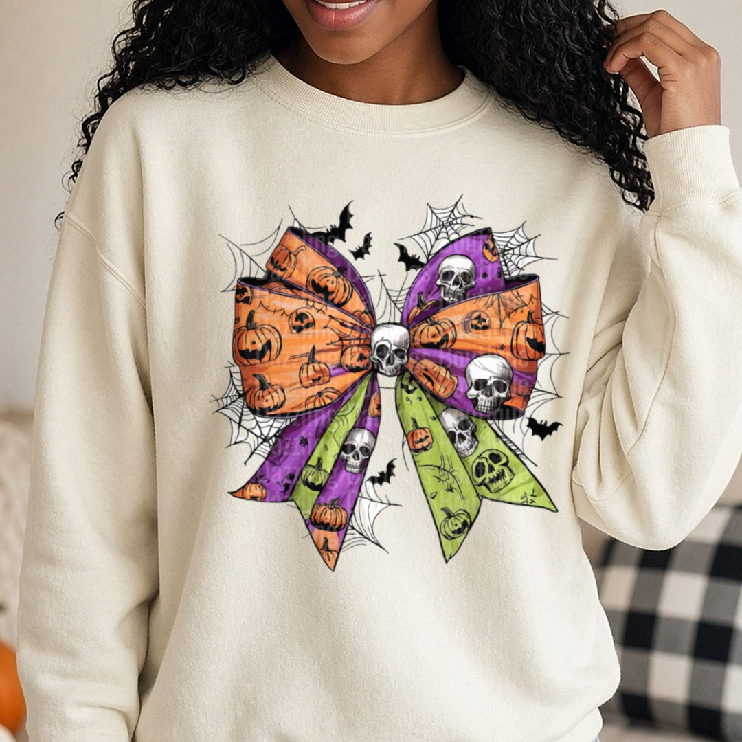 Halloween Fall Coquette Bow Purple Green Orange Skulls DTF transfer shown on a Comfort Colors sweatshirt