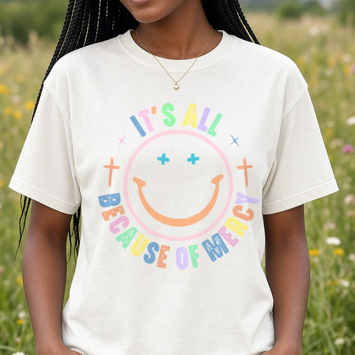 It's All Because of Mercy Smiley DTF transfer shown on a Comfort Colors tee