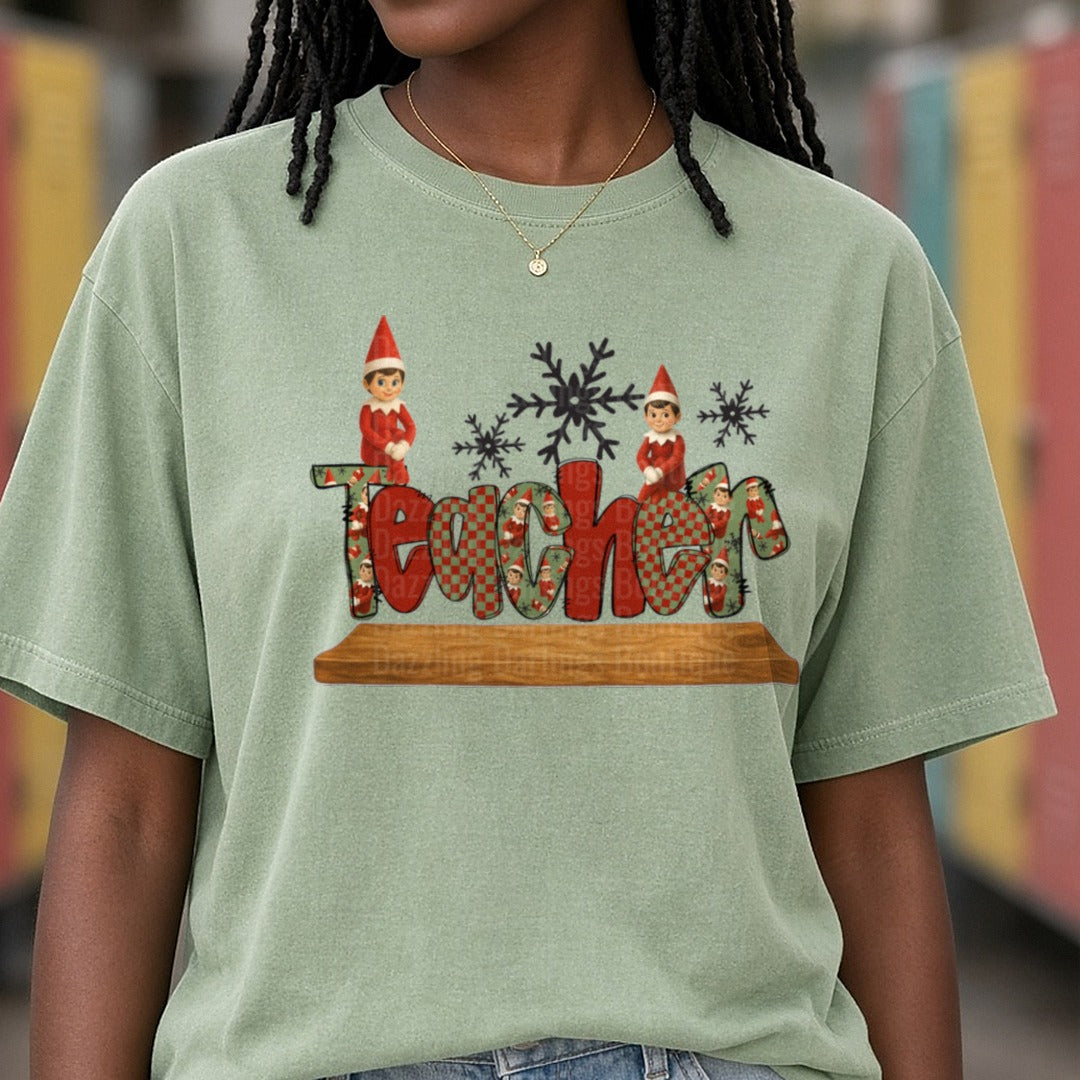 Teacher Christmas Elves Snowflakes Patterned Letters DTF transfer shown on a Comfort Colors tee