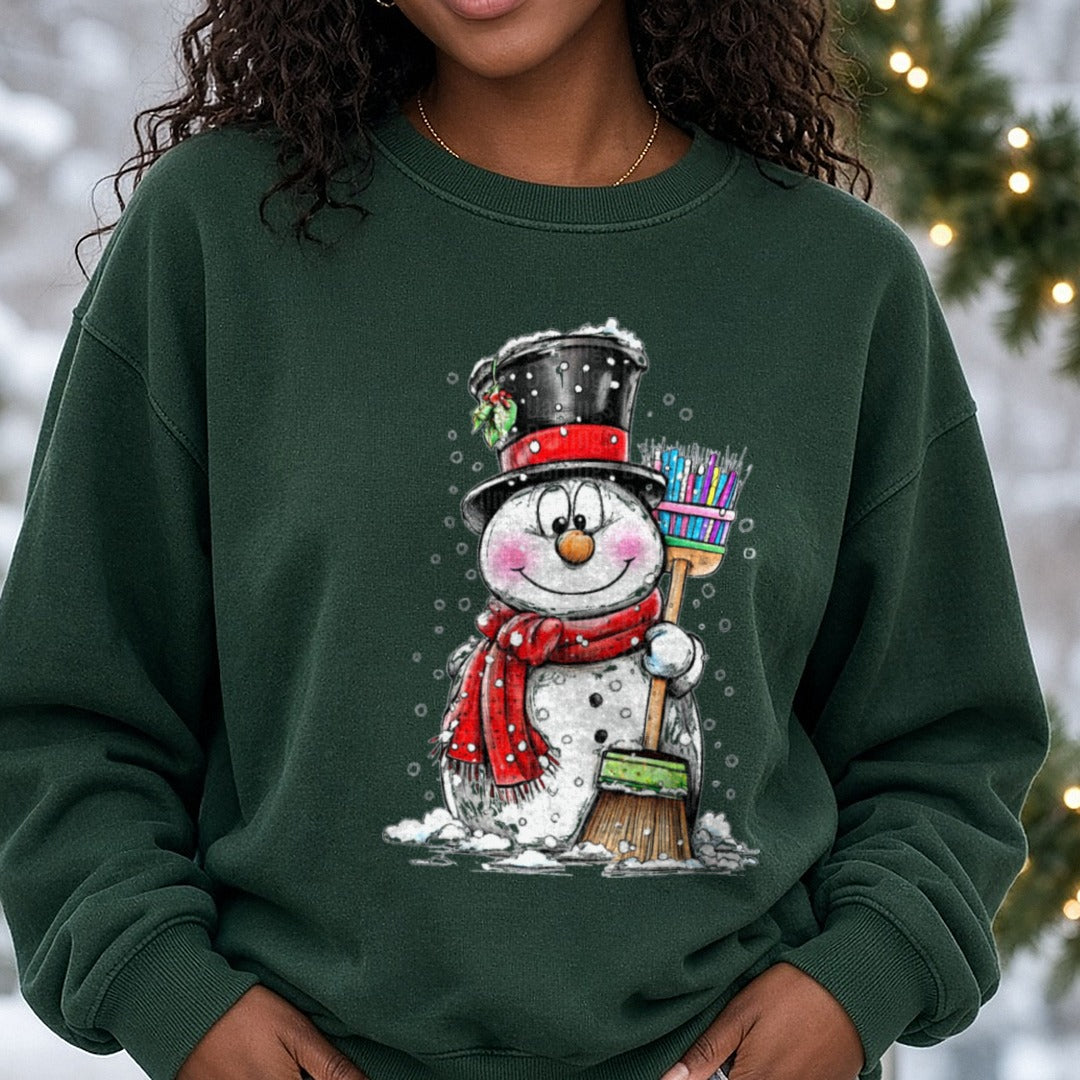 Hand-drawn Snowman Colorful Broom Black Hat DTF transfer shown on a Comfort Colors sweatshirt
