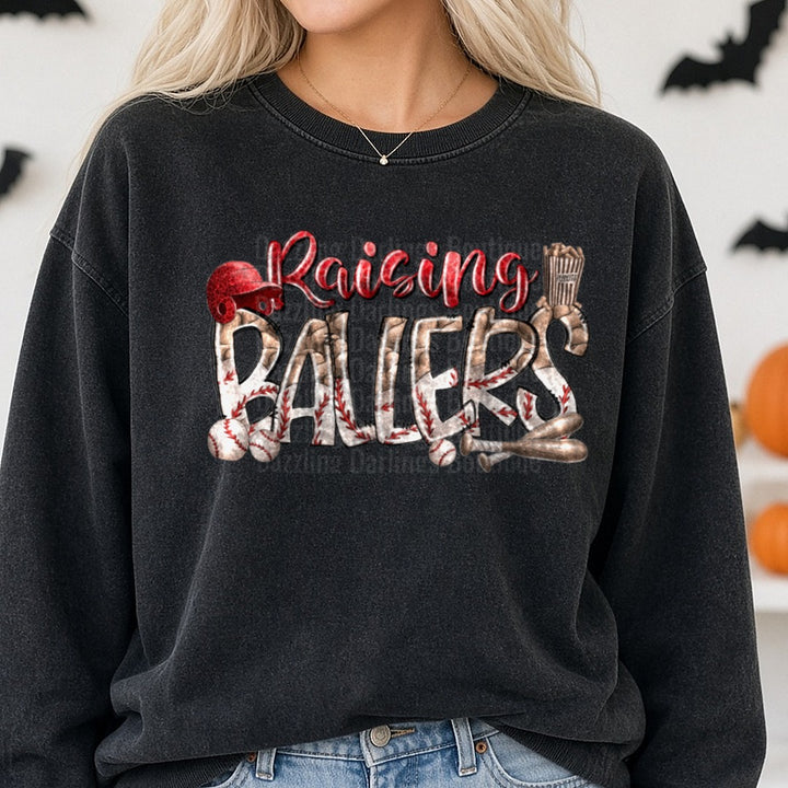Raising Ballers Baseball Typography with Helmet Bat and Peanuts DTF transfer shown on a Comfort Colors sweatshirt