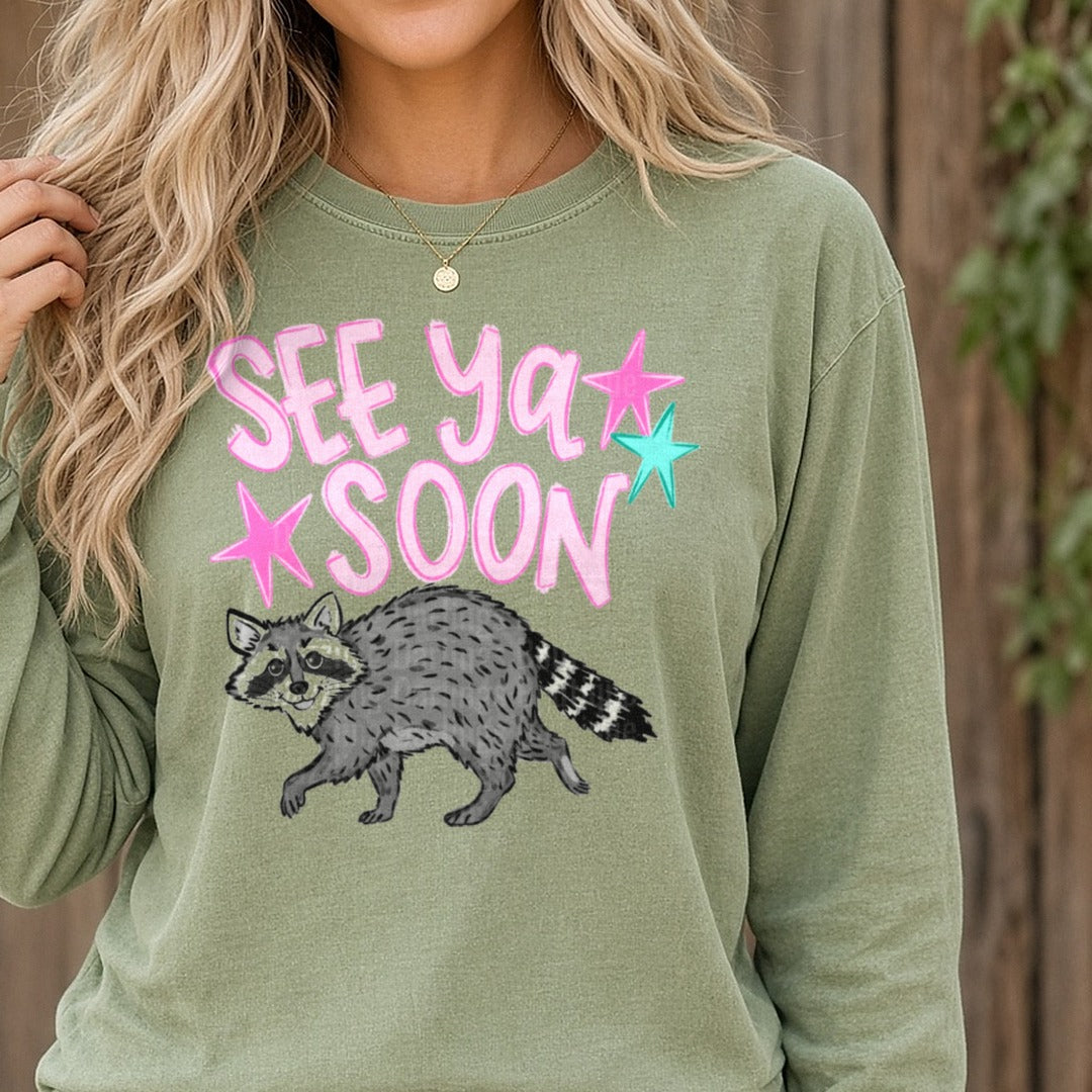 See Ya Soon Raccoon with Pink Stars DTF transfer shown on a Comfort Colors long sleeve tee