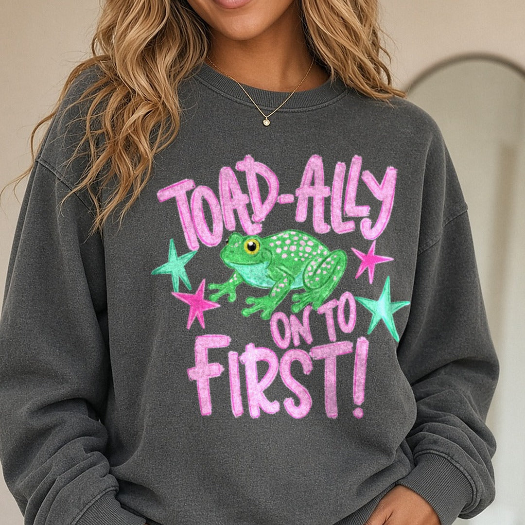 Toad-ally On To First Cute Frog with Pink Stars DTF transfer shown on a Comfort Colors sweatshirt