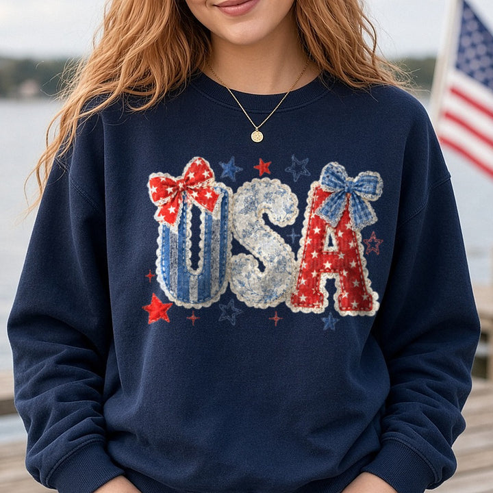 Patriotic USA Letters Fabric Applique Bows Stars Red White Blue DTF transfer shown on a Comfort Colors sweatshirt