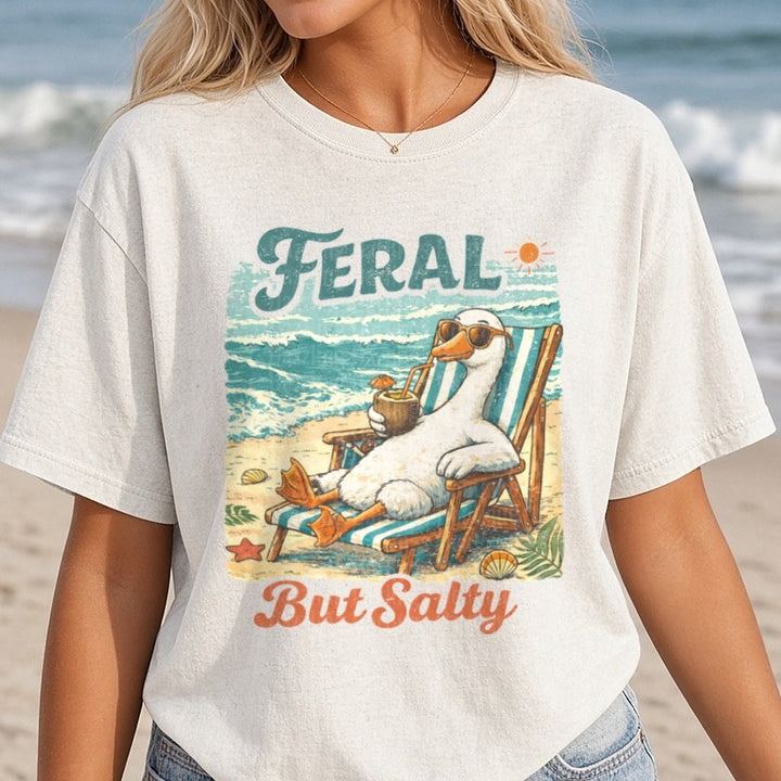 Feral But Salty Goose Relaxing on Beach Chair with Coconut Drink DTF transfer shown on a Comfort Colors tee