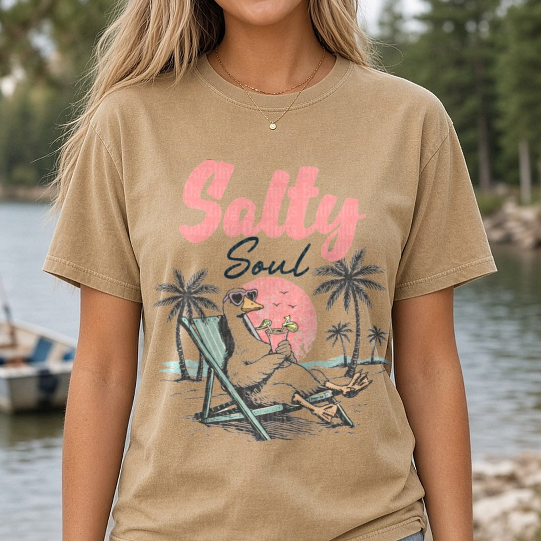 Salty Soul Beach Duck Relaxing in Lounge Chair with Cocktail DTF transfer shown on a Comfort Colors tee
