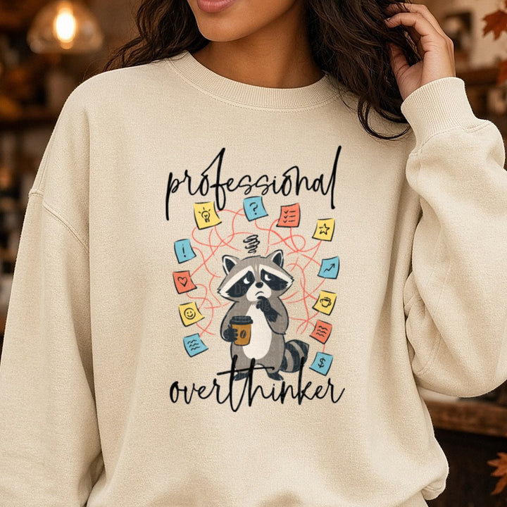 Professional Overthinker Anxious Raccoon with Coffee DTF transfer shown on a Comfort Colors sweatshirt