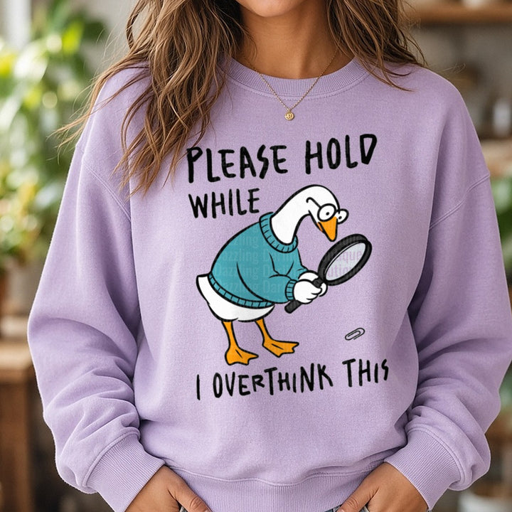 Please Hold While I Overthink This Funny Goose With Magnifying Glass DTF transfer shown on a Comfort Colors sweatshirt
