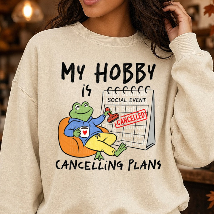 My Hobby Is Cancelling Plans Cozy Frog Introvert Humor DTF transfer shown on a Comfort Colors sweatshirt