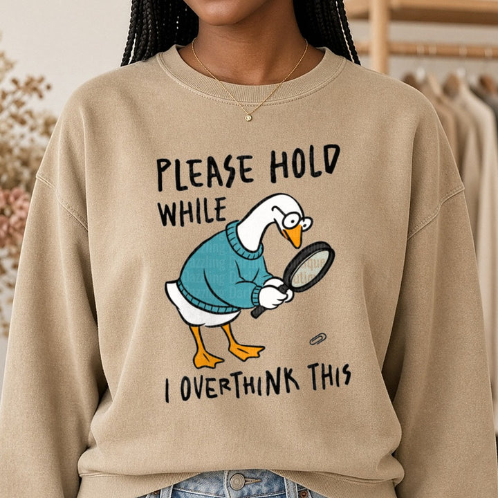 Please Hold While I Overthink This Funny Goose With Magnifying Glass DTF transfer shown on a Comfort Colors sweatshirt