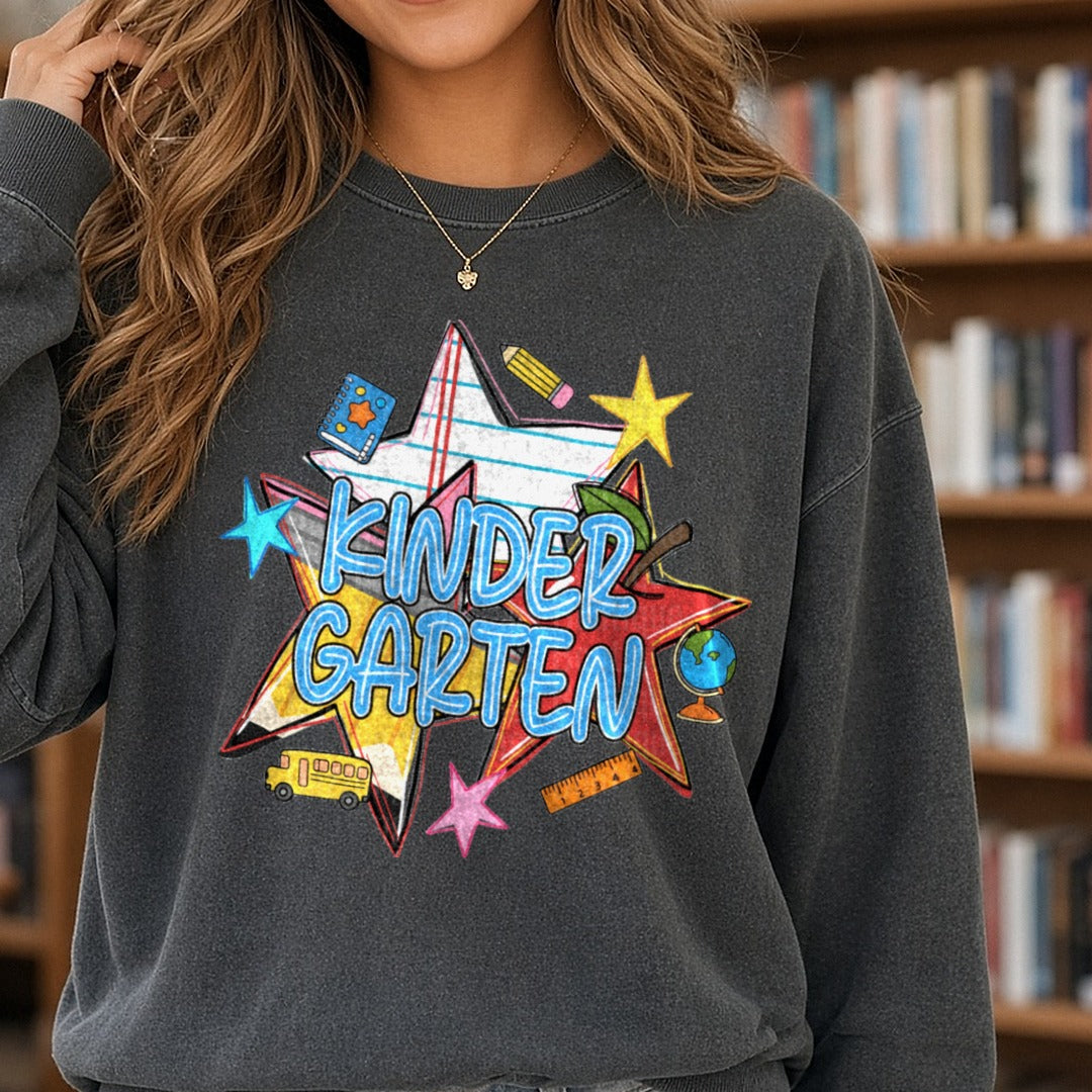 Kindergarten Bold Stars School Supplies Back to School DTF transfer shown on a Comfort Colors sweatshirt
