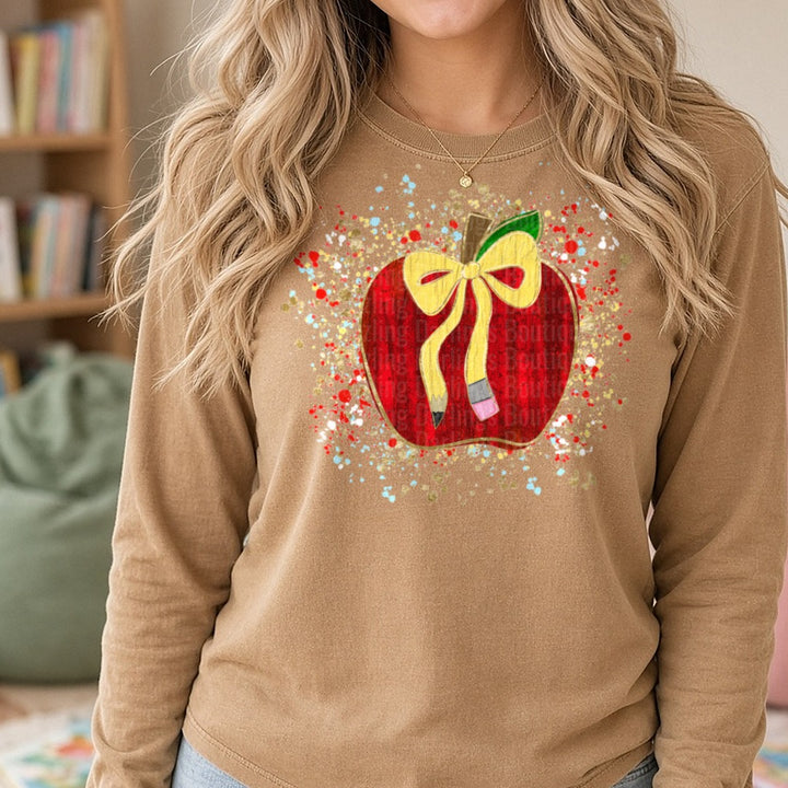 Red Apple Pencil Bow Teacher Gold Glitter Paint Splatter DTF transfer shown on a Comfort Colors long sleeve tee