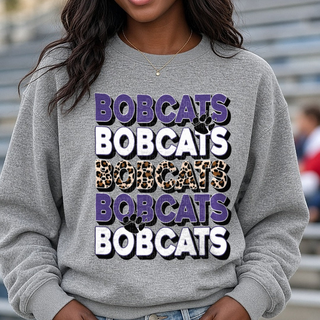 Bobcats Stacked Word Repeat Purple Leopard Print Paw Print DTF transfer shown on a Comfort Colors sweatshirt