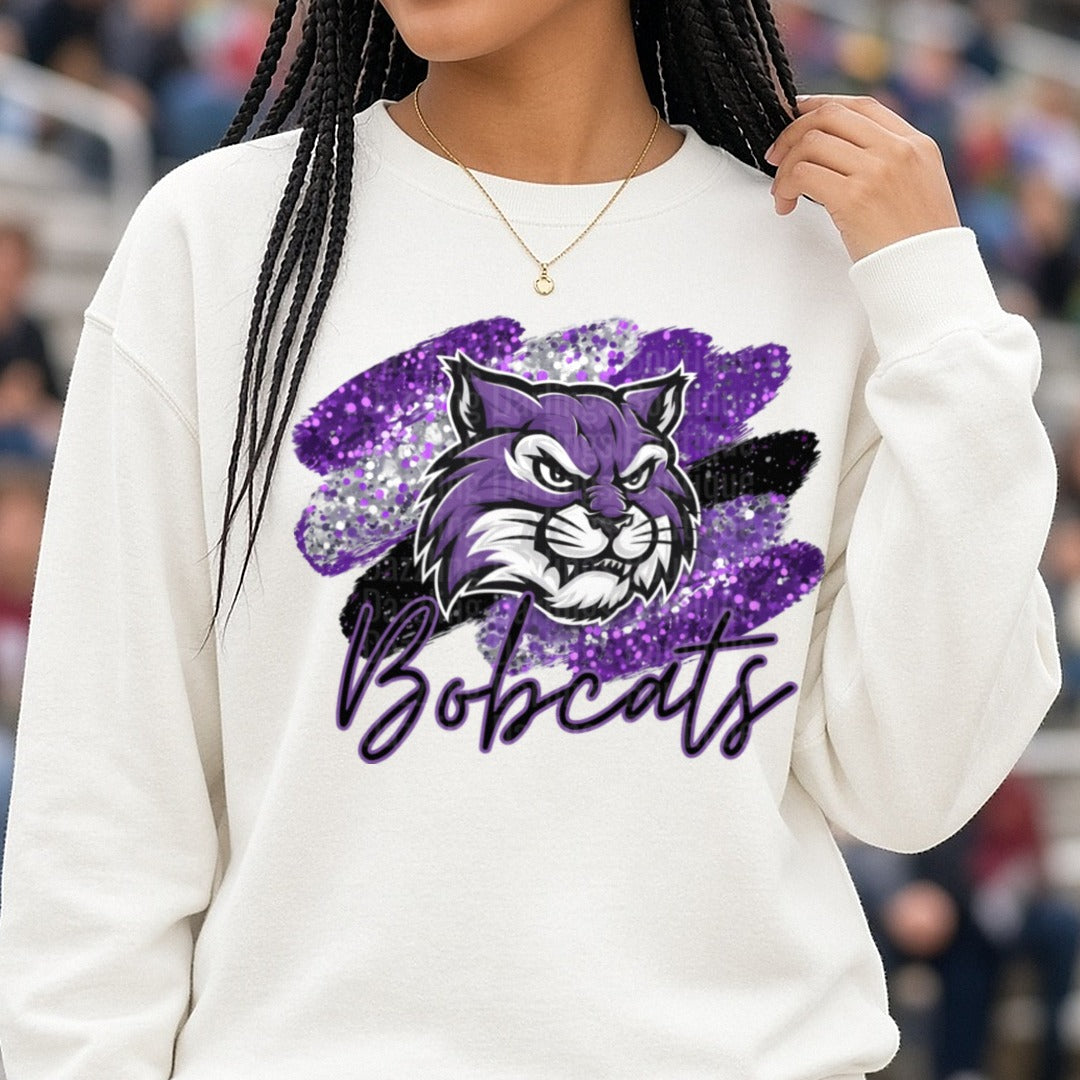 Purple Glitter Bobcats Mascot Script Brushstroke Design DTF transfer shown on a Comfort Colors sweatshirt