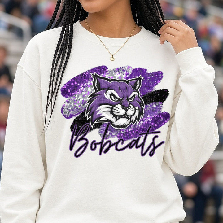 Purple Glitter Bobcats Mascot Script Brushstroke Design DTF transfer shown on a Comfort Colors sweatshirt