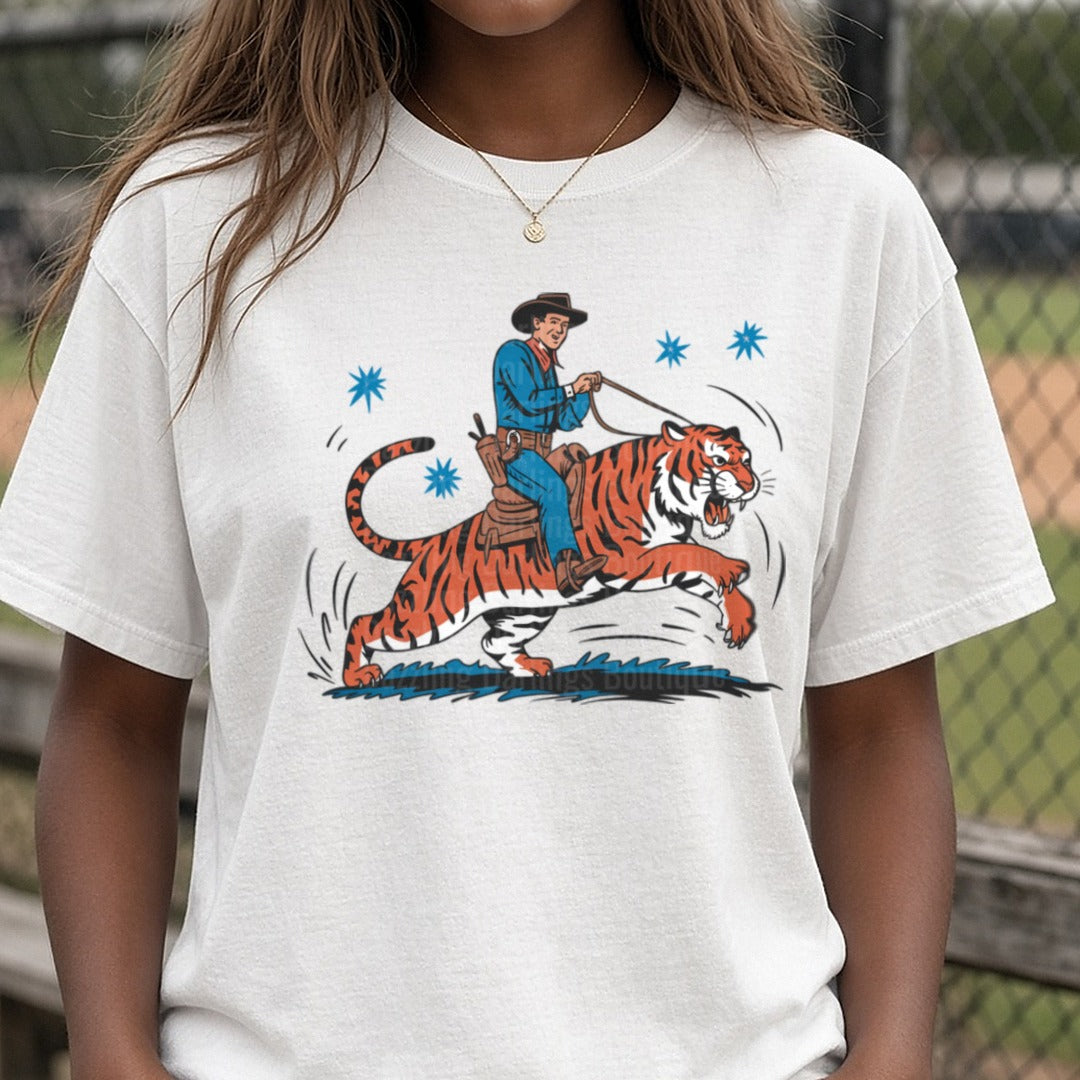 Retro Cowboy Riding a Wild Tiger with Blue Stars DTF transfer shown on a Comfort Colors tee