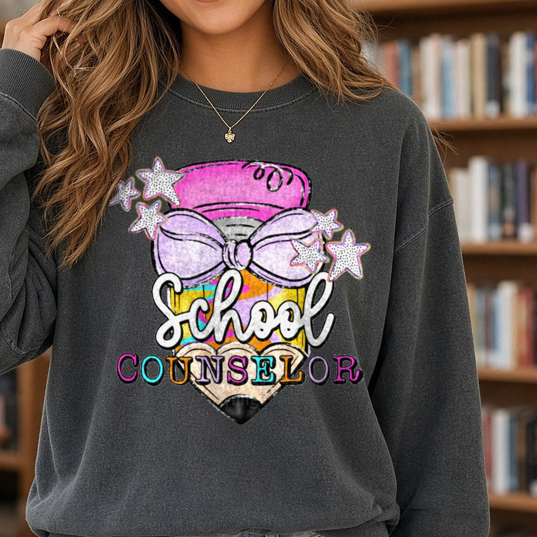 School Counselor Pencil with Purple Bow and Colorful Stars DTF transfer shown on a Comfort Colors sweatshirt