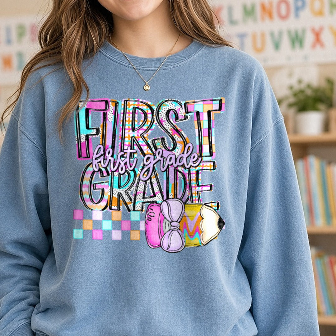 First Grade Colorful Bold Typography Pencil Bow School DTF transfer shown on a Comfort Colors sweatshirt