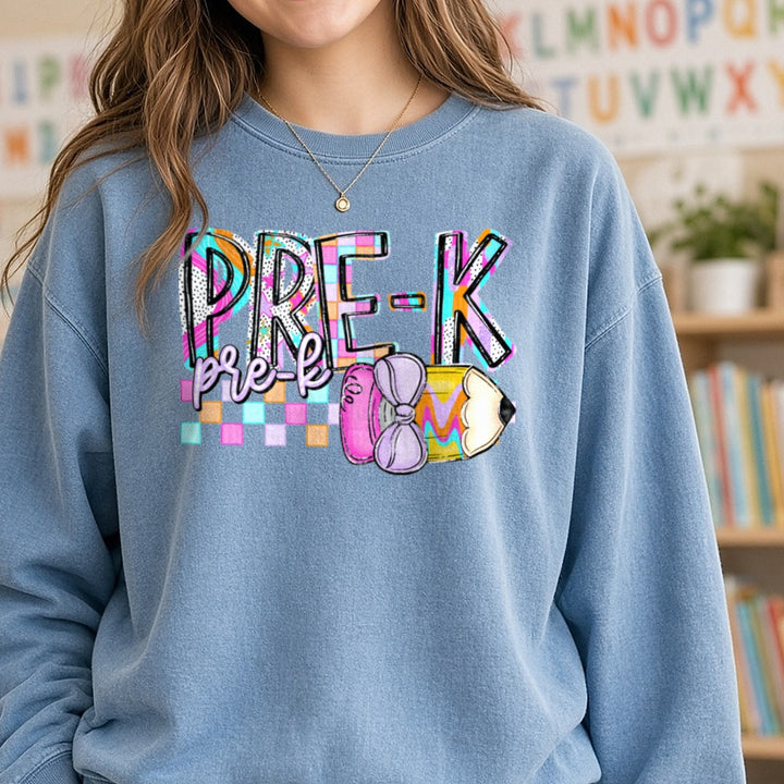 Pre-K Bold Retro Checkered Letters with Pencil and Bow DTF transfer shown on a Comfort Colors sweatshirt