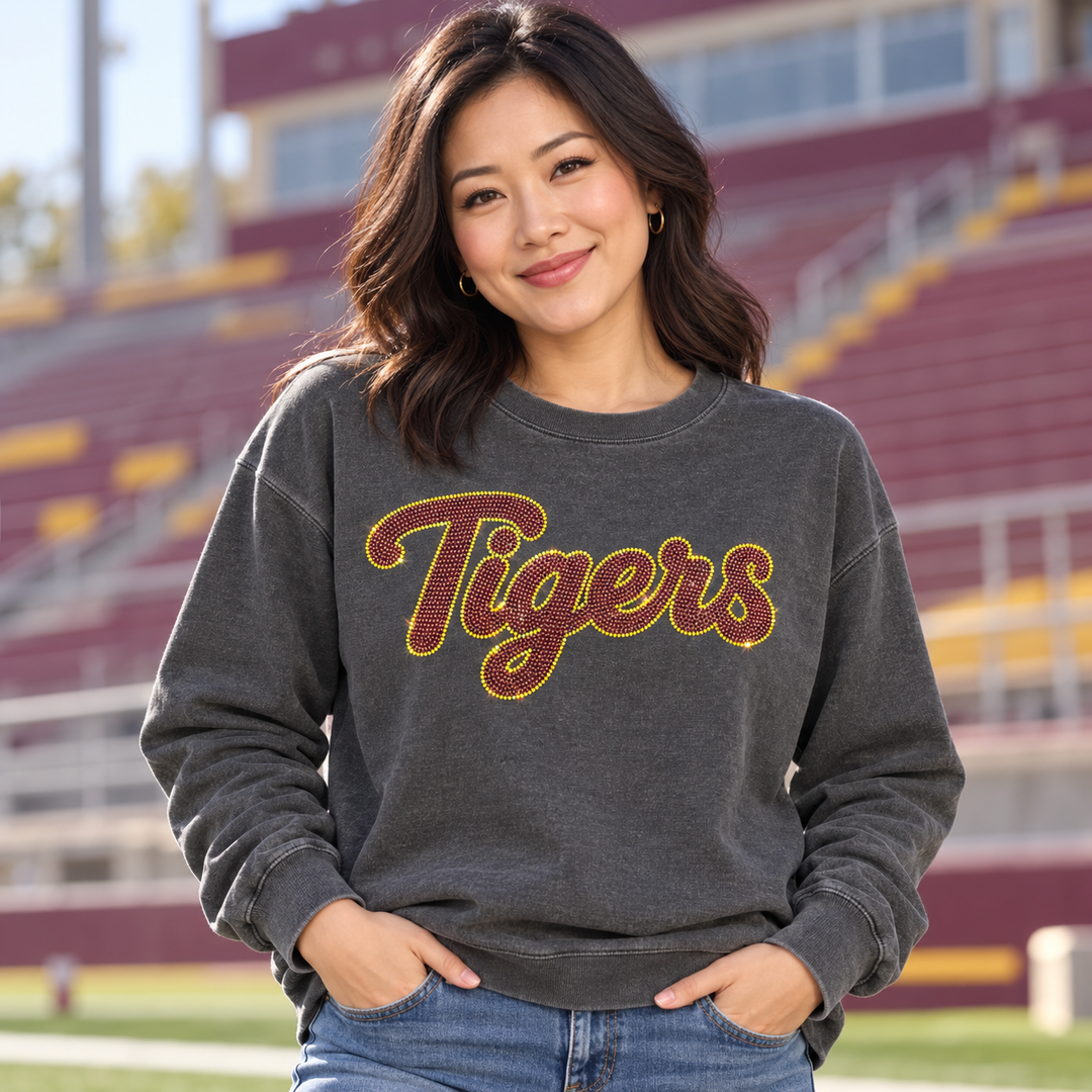Mockup of maroon and gold spangle bling "Tigers" script transfer on a charcoal sweatshirt